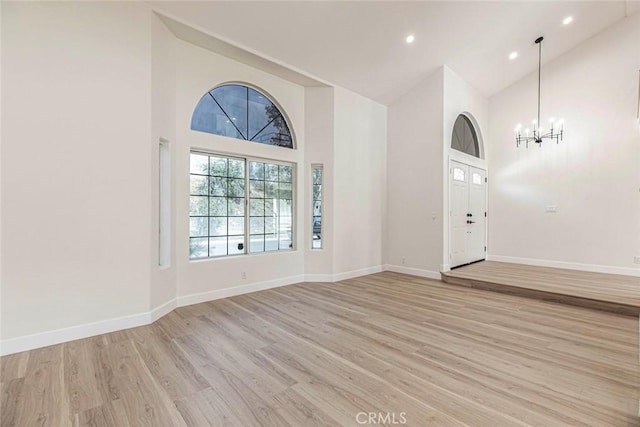 entryway featuring high vaulted ceiling, a chandelier, light wood-style flooring, baseboards, and recessed lighting