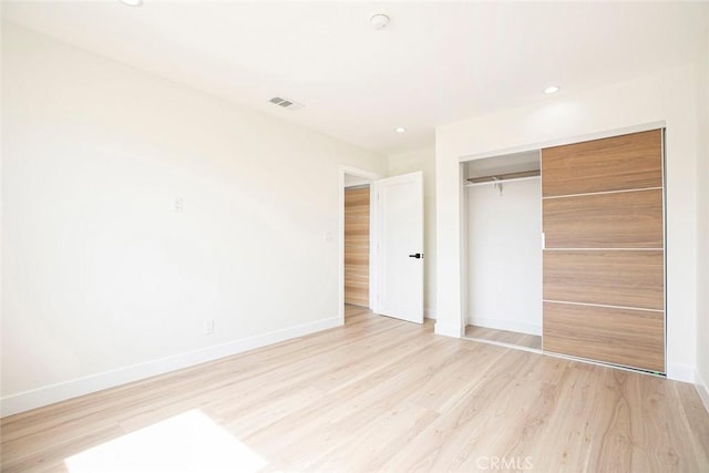 unfurnished bedroom featuring baseboards, light wood-type flooring, a closet, and recessed lighting
