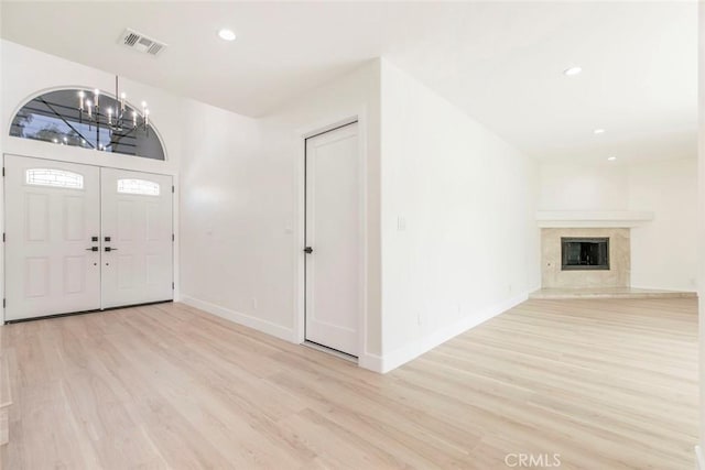 foyer entrance with a chandelier, light wood-style flooring, baseboards, recessed lighting, and a fireplace