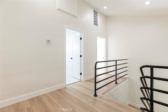 hall featuring baseboards, wood finished floors, recessed lighting, and an upstairs landing