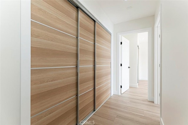 corridor with baseboards and light wood-style floors