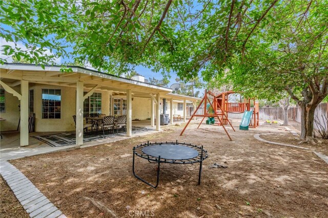 view of playground with fence, a patio, and a trampoline