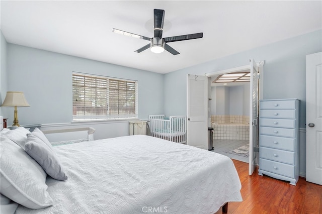 bedroom with wood finished floors, a ceiling fan, and ensuite bathroom