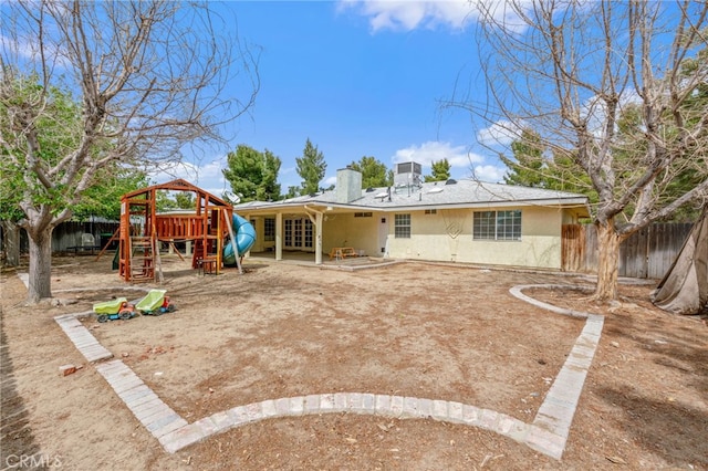 back of house with a playground, fence, stucco siding, and french doors
