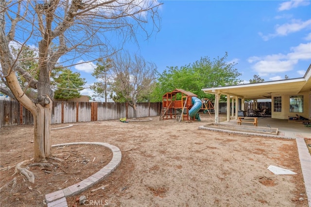 fenced backyard with a playground, ceiling fan, and a patio