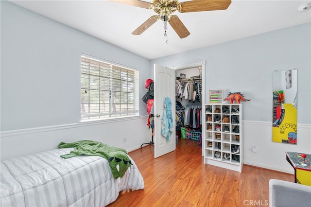 bedroom featuring a closet, wood finished floors, a spacious closet, and a ceiling fan