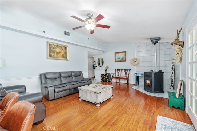 living area with light wood finished floors, ceiling fan, a wood stove, and lofted ceiling