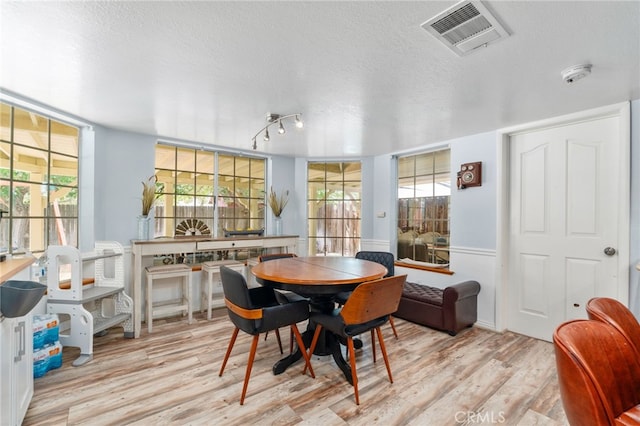 dining room with a textured ceiling, wood finished floors, and healthy amount of natural light