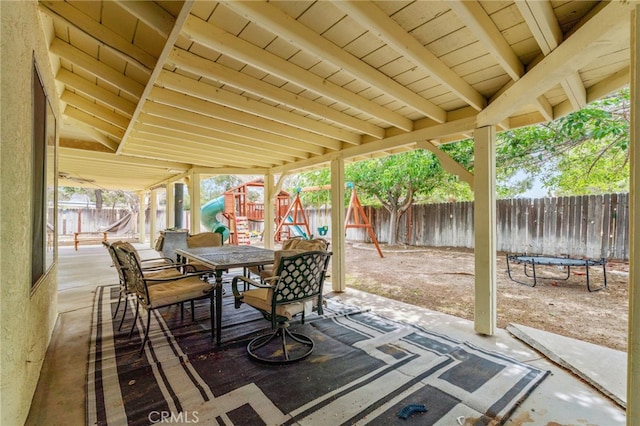 view of patio featuring a playground, a fenced backyard, and outdoor dining space