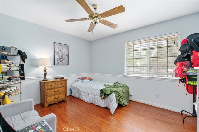 bedroom with wood finished floors, baseboards, and a ceiling fan