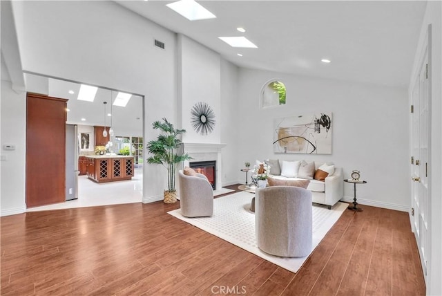 9588 Shimizu River Cir, Fountain Valley, CA 92708 - living area featuring a skylight, a glass covered fireplace, wood finished floors, high vaulted ceiling, and plenty of natural light
