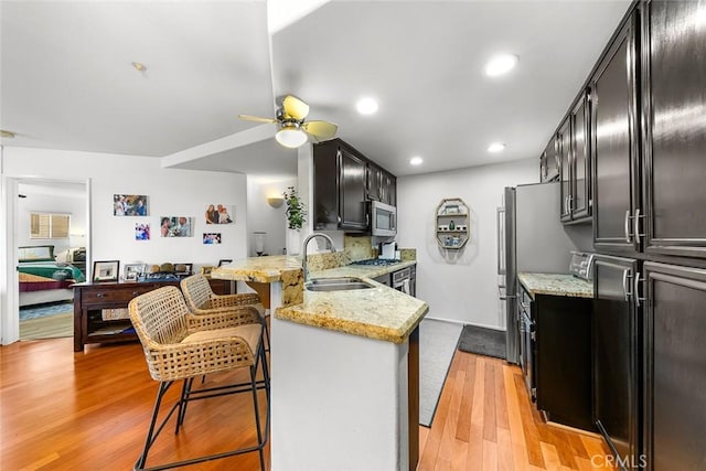 11165 Affinity Ct Unit 32, San Diego, CA 92131 - kitchen with stainless steel microwave, a sink, dark cabinets, a peninsula, and recessed lighting