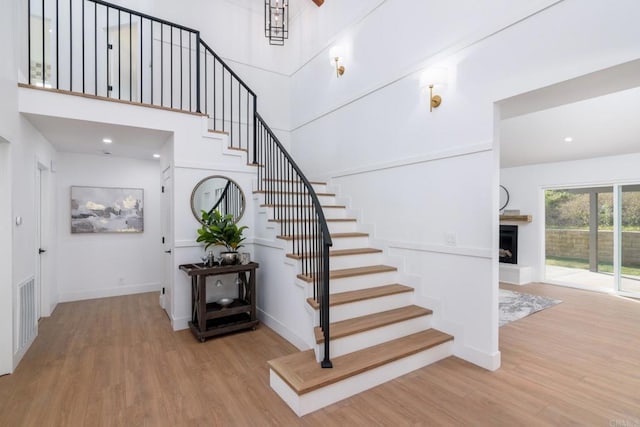 1142 Cabot Ct, Vista, CA 92081 - stairway featuring wood finished floors, baseboards, a fireplace with raised hearth, and a towering ceiling