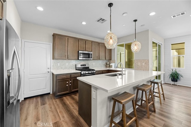 4233 Powell Way Unit 102, Corona, CA 92883 - kitchen with a sink, appliances with stainless steel finishes, dark wood-style floors, a kitchen breakfast bar, and a peninsula