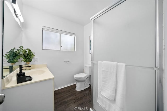 bathroom featuring toilet, wood finished floors, vanity, and baseboards