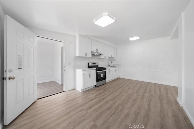 kitchen with stainless steel gas range oven, light countertops, light wood-style flooring, white cabinetry, and under cabinet range hood