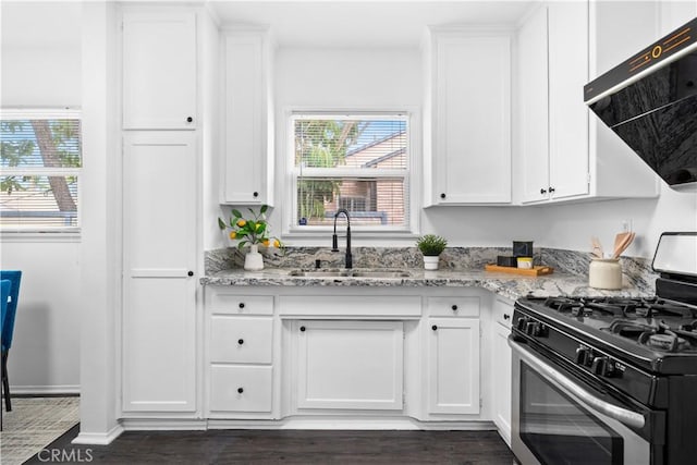 kitchen with gas stove, a sink, exhaust hood, white cabinets, and dark wood finished floors