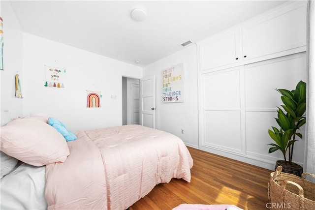 bedroom with wood finished floors and a closet