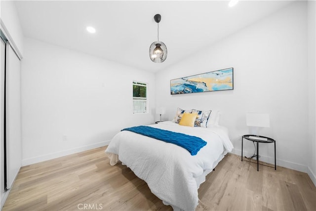bedroom with light wood finished floors, baseboards, recessed lighting, and a closet