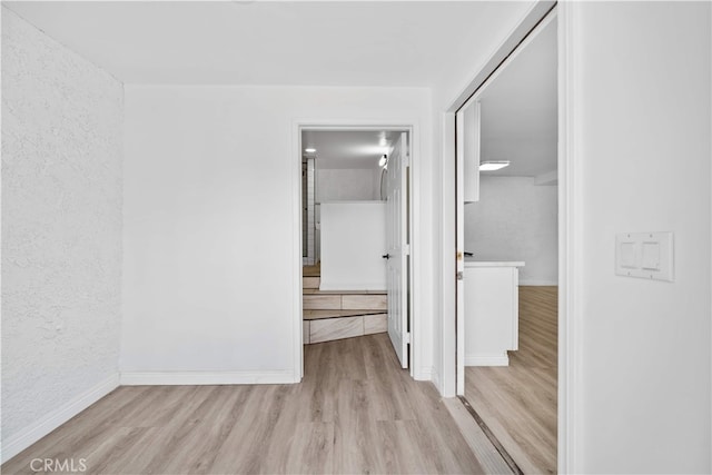 unfurnished bedroom with wood finished floors, baseboards, a textured wall, and a closet