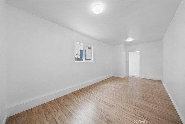 unfurnished room featuring baseboards and light wood-style floors