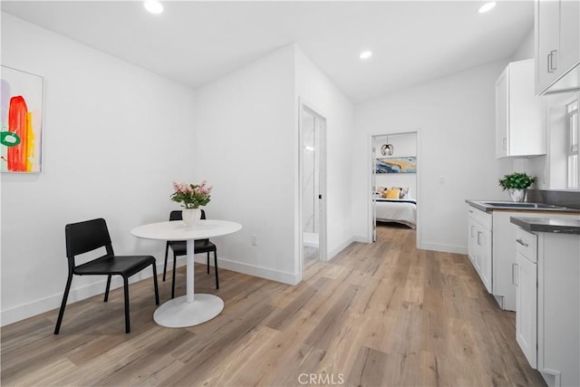 kitchen with white cabinetry, light wood finished floors, dark countertops, recessed lighting, and baseboards