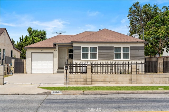view of front of property featuring an attached garage, concrete driveway, a fenced front yard, and roof with shingles