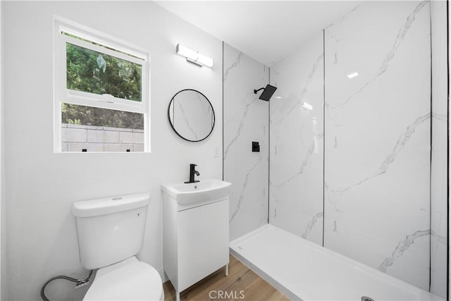 full bath featuring a marble finish shower, toilet, wood finished floors, and vanity