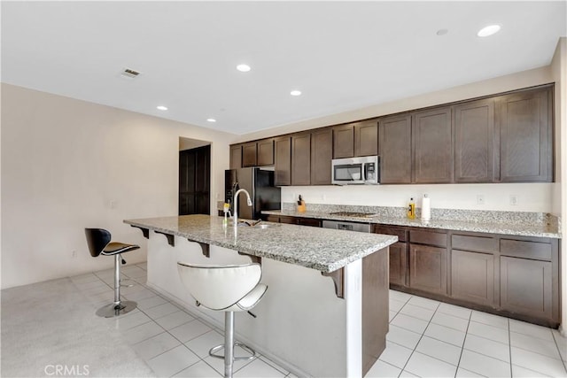 5610 Guardian Way, Chino, CA 91710 - kitchen featuring stainless steel appliances, a kitchen breakfast bar, light tile patterned floors, dark brown cabinetry, and recessed lighting