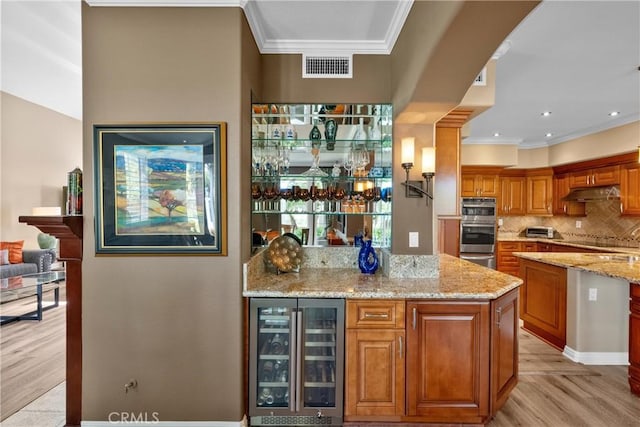 37 Giotto, Aliso Viejo, CA 92656 - indoor wet bar with wine cooler, crown molding, light wood-type flooring, tasteful backsplash, and under cabinet range hood