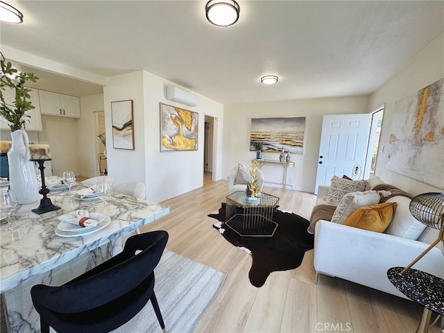 living area with a wall unit AC and light wood-style floors