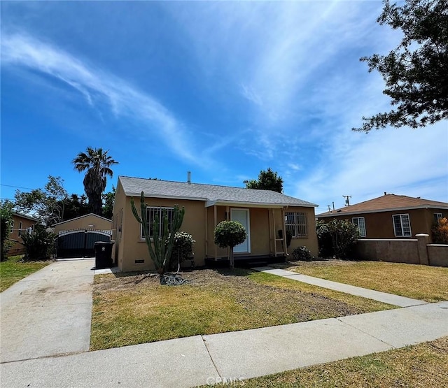 bungalow-style house featuring concrete driveway, stucco siding, a front lawn, and a gate