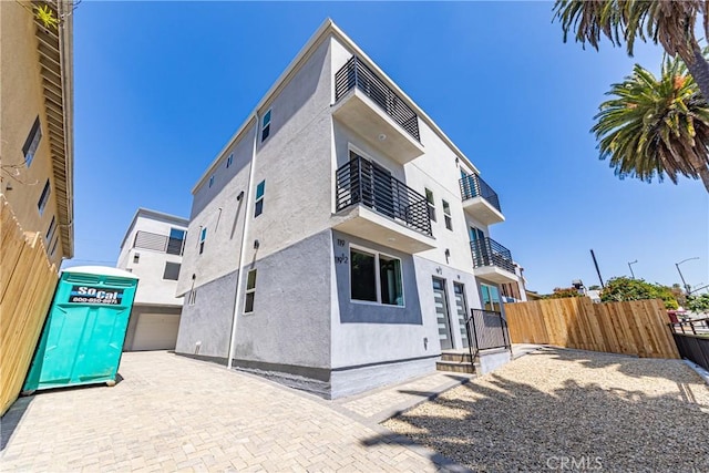 view of home's exterior featuring stucco siding, fence, a balcony, and a patio