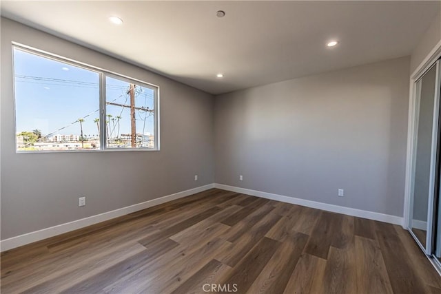 spare room featuring dark wood finished floors, recessed lighting, and baseboards