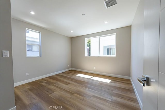 empty room featuring plenty of natural light, wood finished floors, baseboards, and recessed lighting