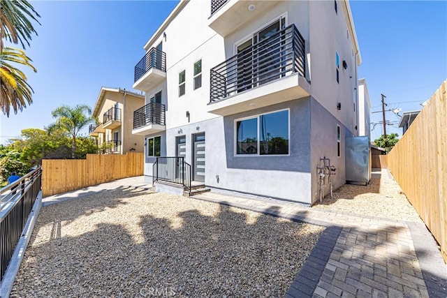 back of property featuring stucco siding, a fenced backyard, and a balcony