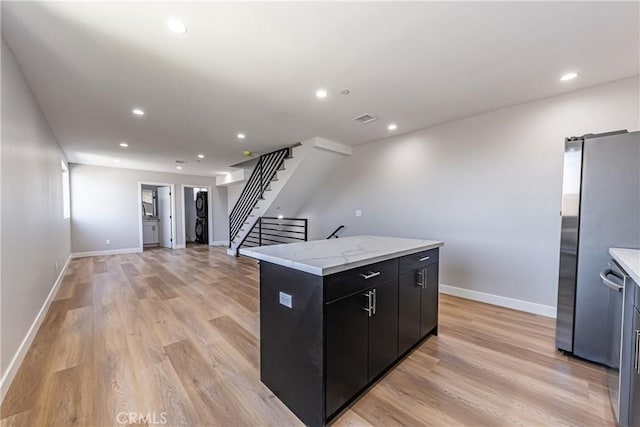 kitchen with dark cabinets, a center island, light wood finished floors, freestanding refrigerator, and recessed lighting