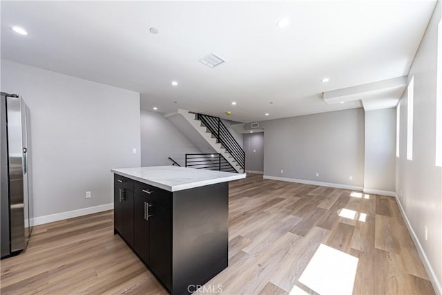kitchen with freestanding refrigerator, light wood-type flooring, a center island, baseboards, and recessed lighting