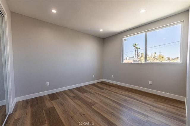 spare room featuring dark wood-style flooring, baseboards, and recessed lighting