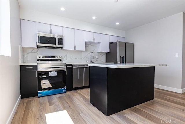 kitchen with appliances with stainless steel finishes, light countertops, baseboards, light wood-style floors, and recessed lighting