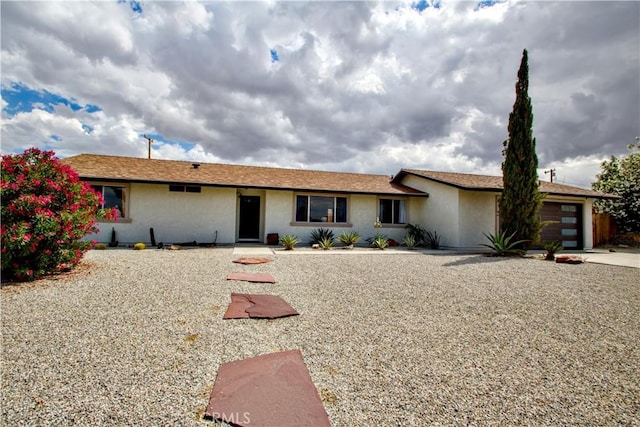 ranch-style house featuring a garage, stucco siding, and concrete driveway