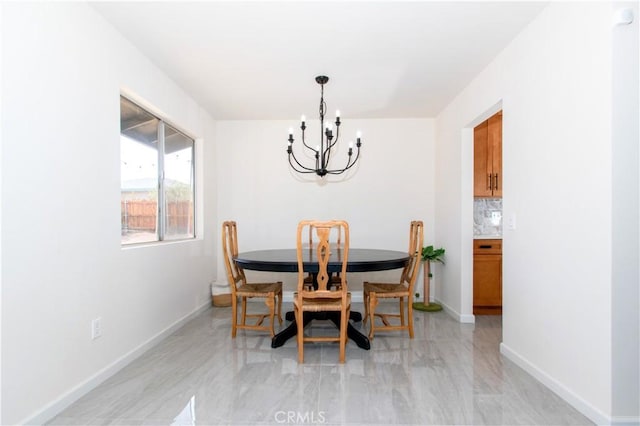 dining space featuring a chandelier and baseboards