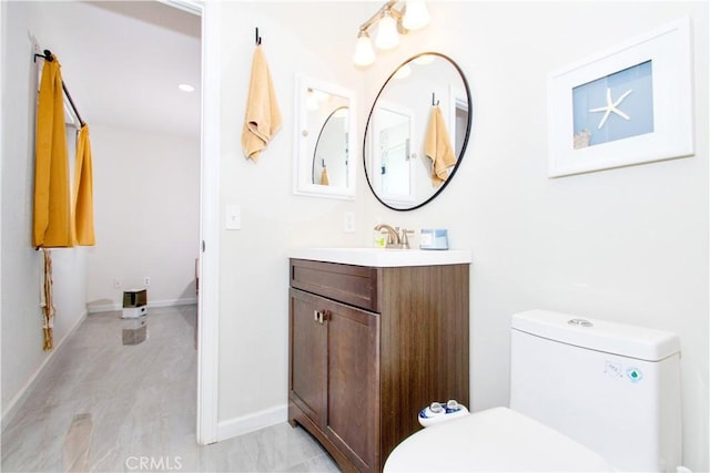 bathroom with toilet, vanity, and baseboards