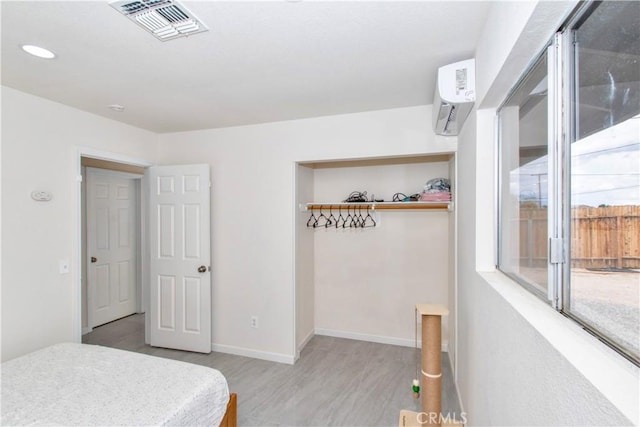 bedroom with a wall mounted AC, light wood-style floors, access to outside, and baseboards