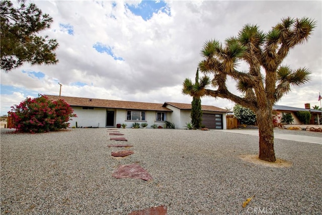 ranch-style home featuring concrete driveway, an attached garage, and stucco siding