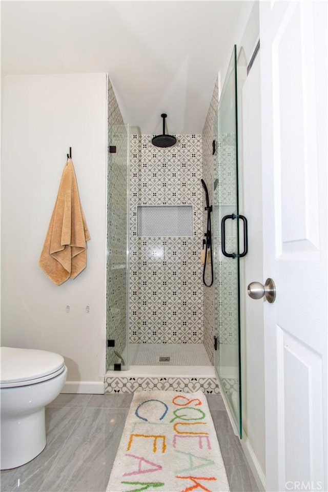 full bath with toilet, baseboards, a shower stall, and tile patterned flooring