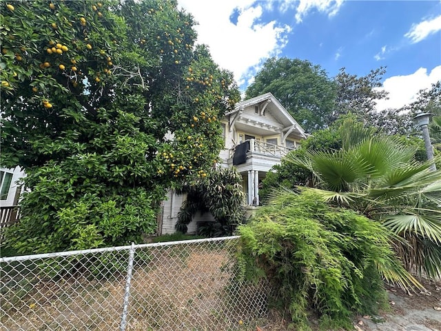 view of property exterior featuring a balcony and fence