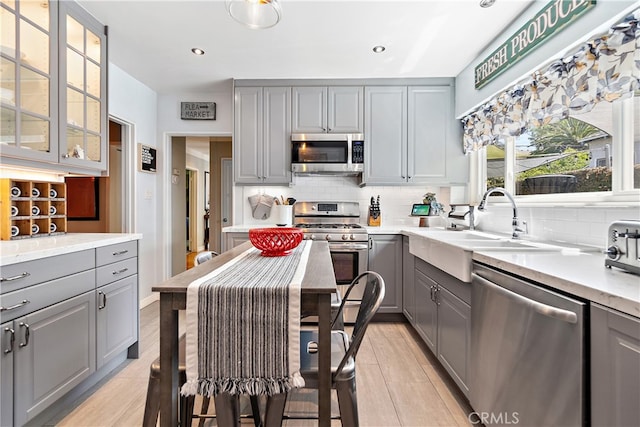 13611 Walnut St, Whittier, CA 90602 - kitchen with gray cabinetry, stainless steel appliances, backsplash, glass insert cabinets, and a sink