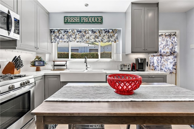 13611 Walnut St, Whittier, CA 90602 - kitchen featuring gray cabinetry, appliances with stainless steel finishes, a sink, and decorative backsplash