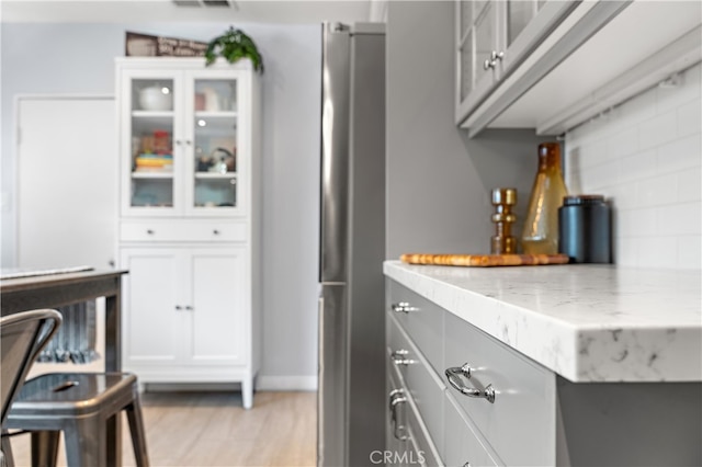 13611 Walnut St, Whittier, CA 90602 - kitchen with backsplash, gray cabinetry, light stone counters, glass insert cabinets, and white cabinetry